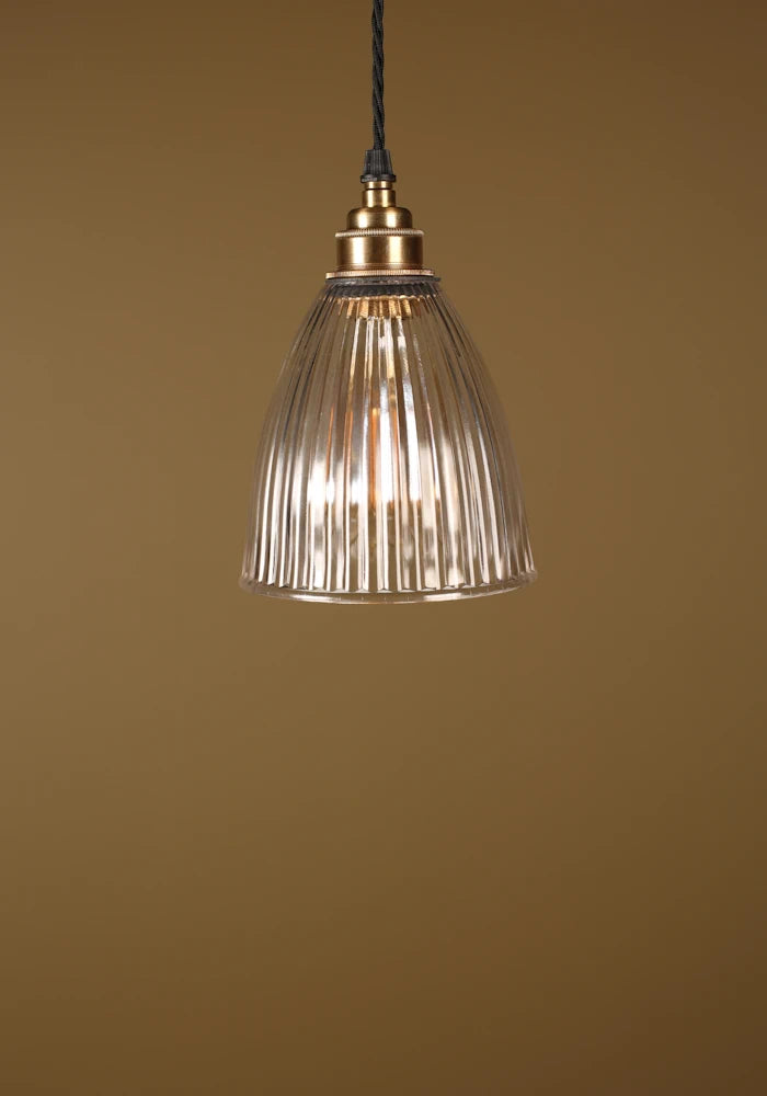 Small prismatic glass pendant light, brass lamp holder on beige background
