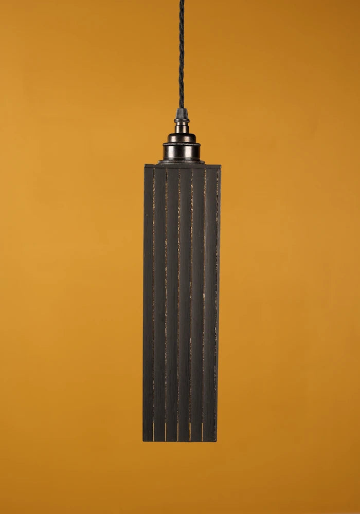 Black pendant light against a mustard yellow background with bronze lamp holder