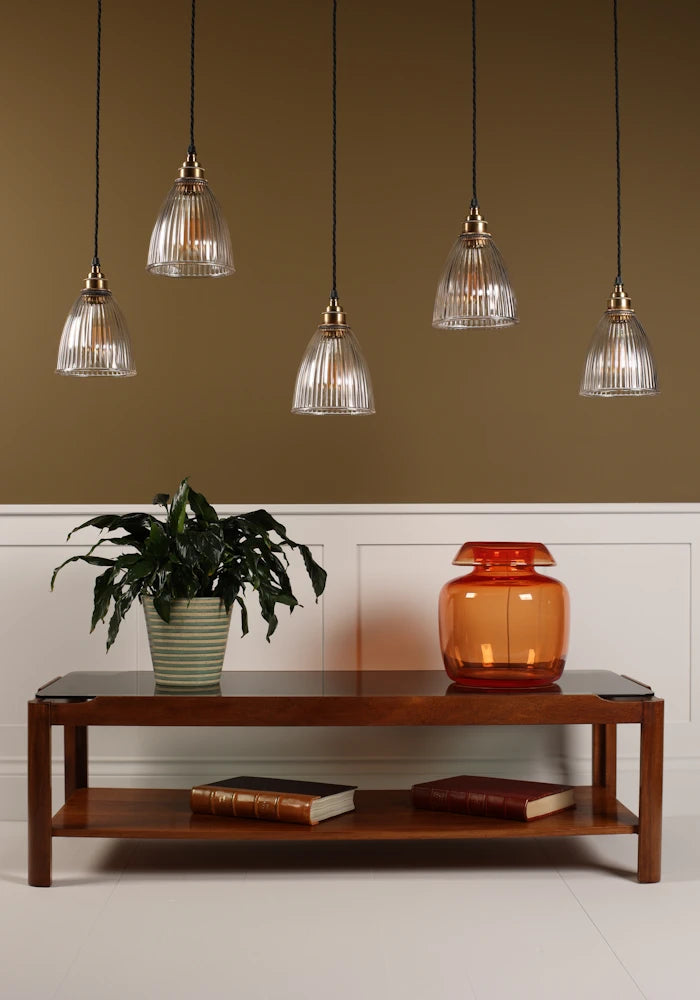 Cluster of prismatic glass pendant lights hanging over coffee table with vase, plant with beige background
