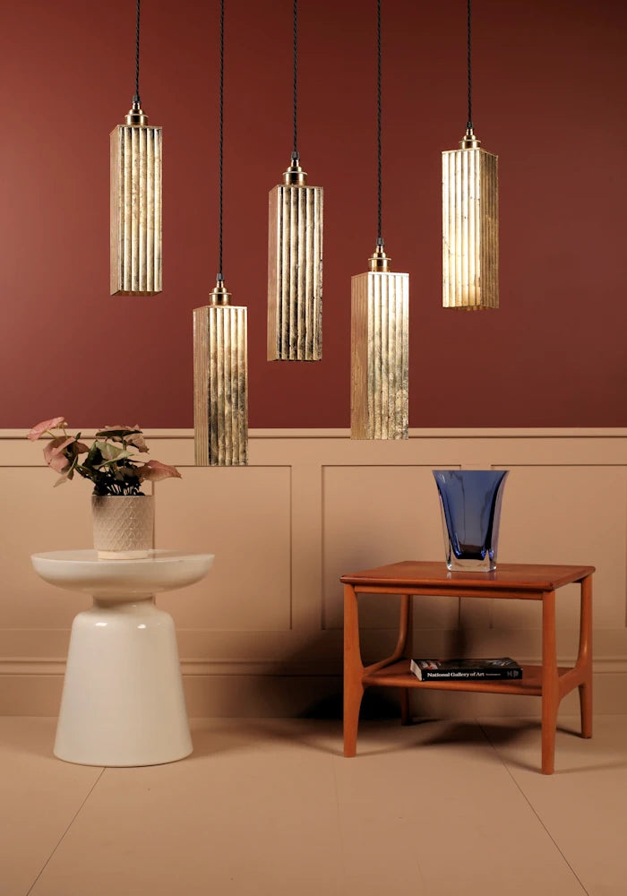 Decorative pendant lights hanging above a table with a vase and books against a red wall.
