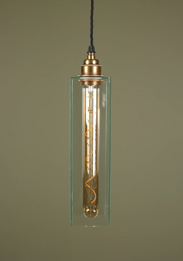 Elegant long clear glass pendant light with brass lamp holder, sage green background