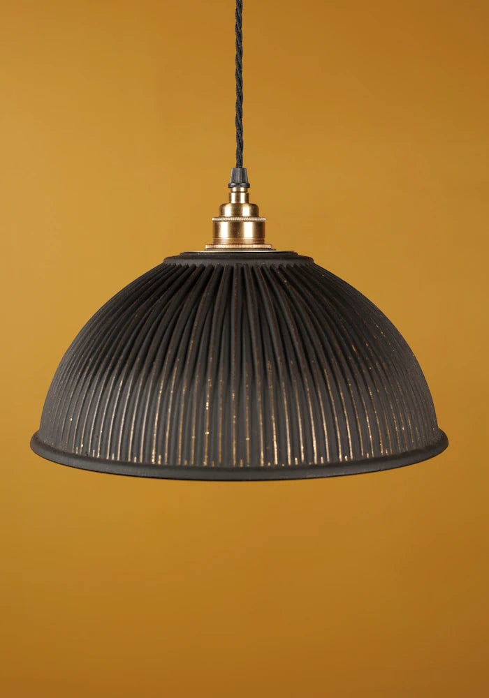 Black & gold dome prismatic glass pendant light with brass lamp holder on mustard yellow background