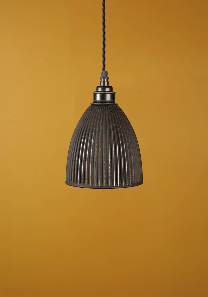 Black pendant light with bronze lamp holder against a mustard yellow background