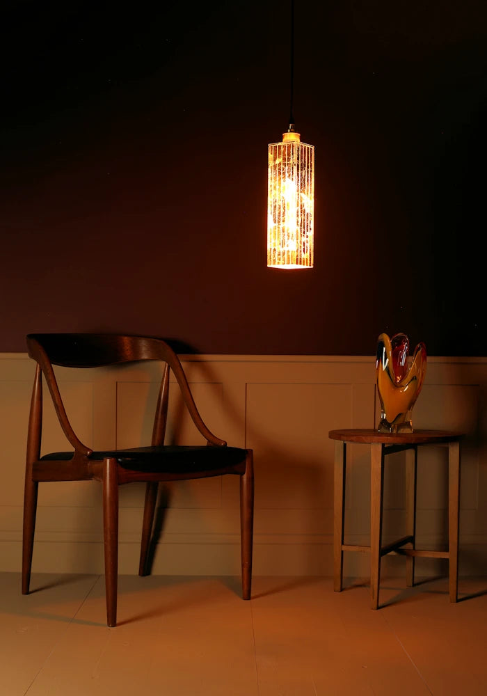 Modern chair and table with a hanging light fixture against a dark wall.