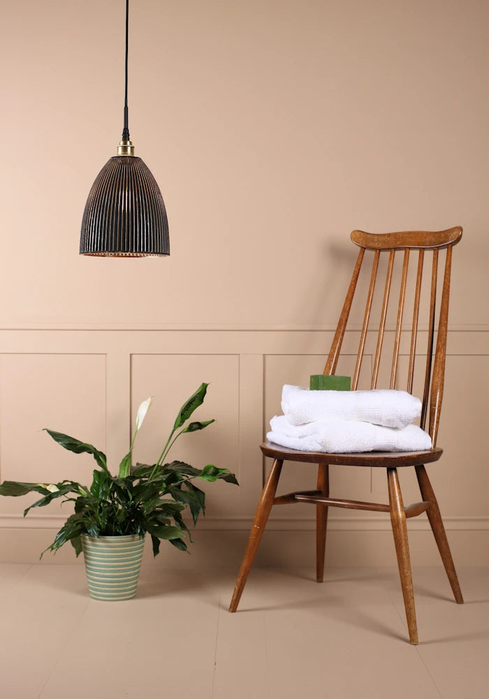 Black and gold bell shaped ribbed glass bathroom pendant light switched off with plant and wooden chair 