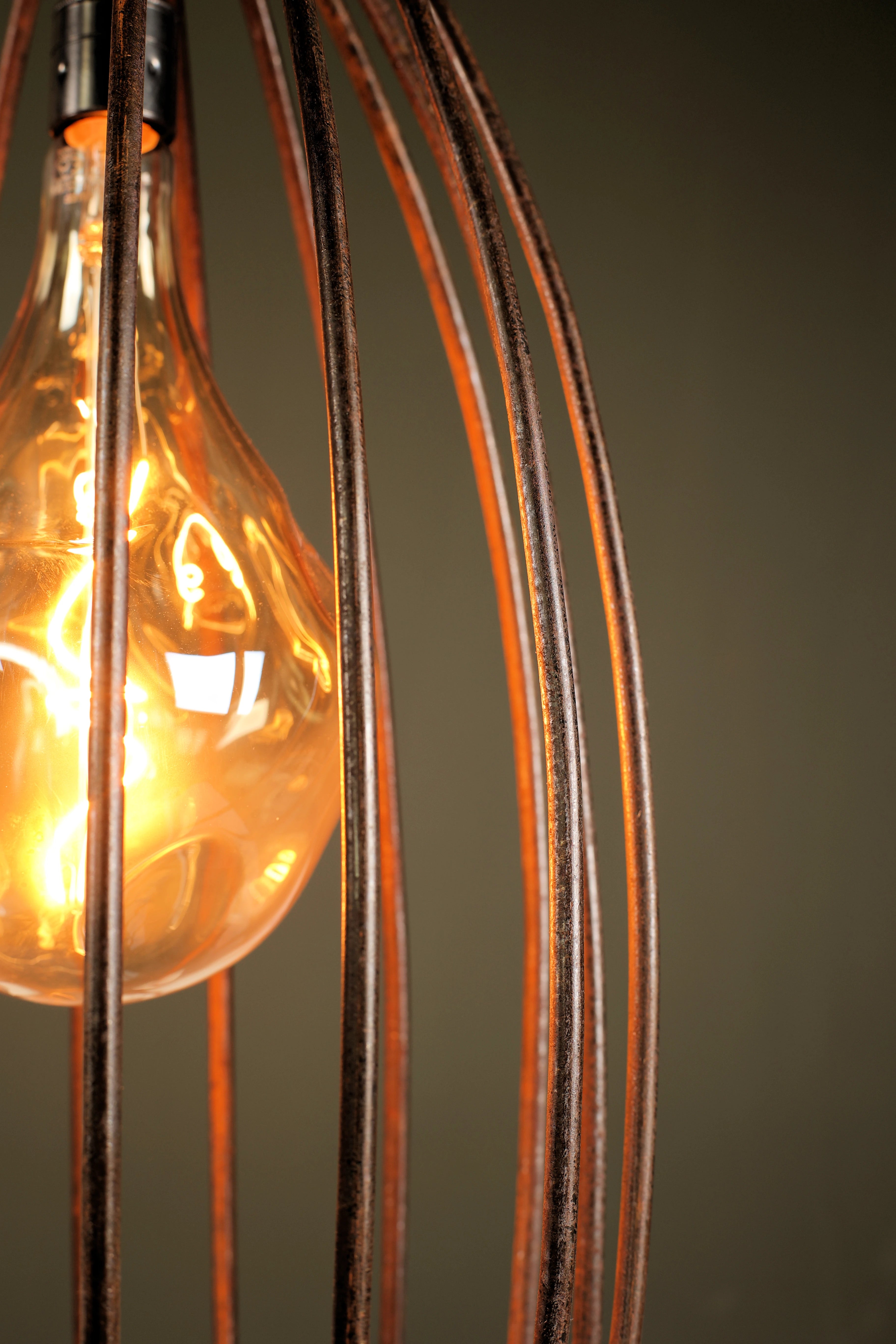 Vintage-style light bulb in a decorative metal cage against a dark background