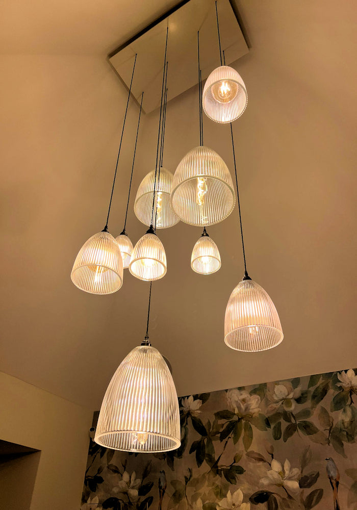 Cluster of different size ribbed glass pendant lights hanging from ceiling rose