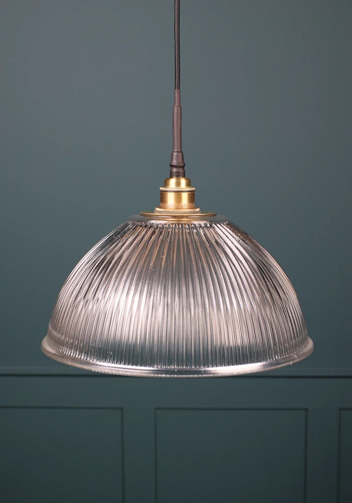 A large glass dome bathroom pendant light with brushed brass lamp holder and black fabric flex