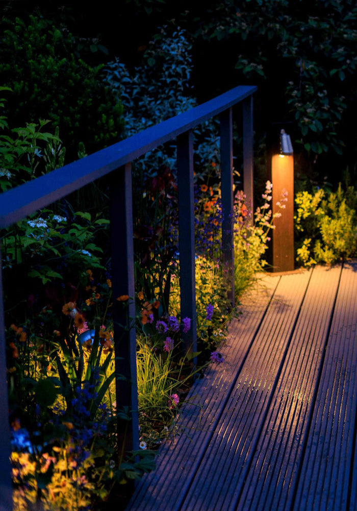 Decorative Bamboo garden path light, decking and plants lit up at night 