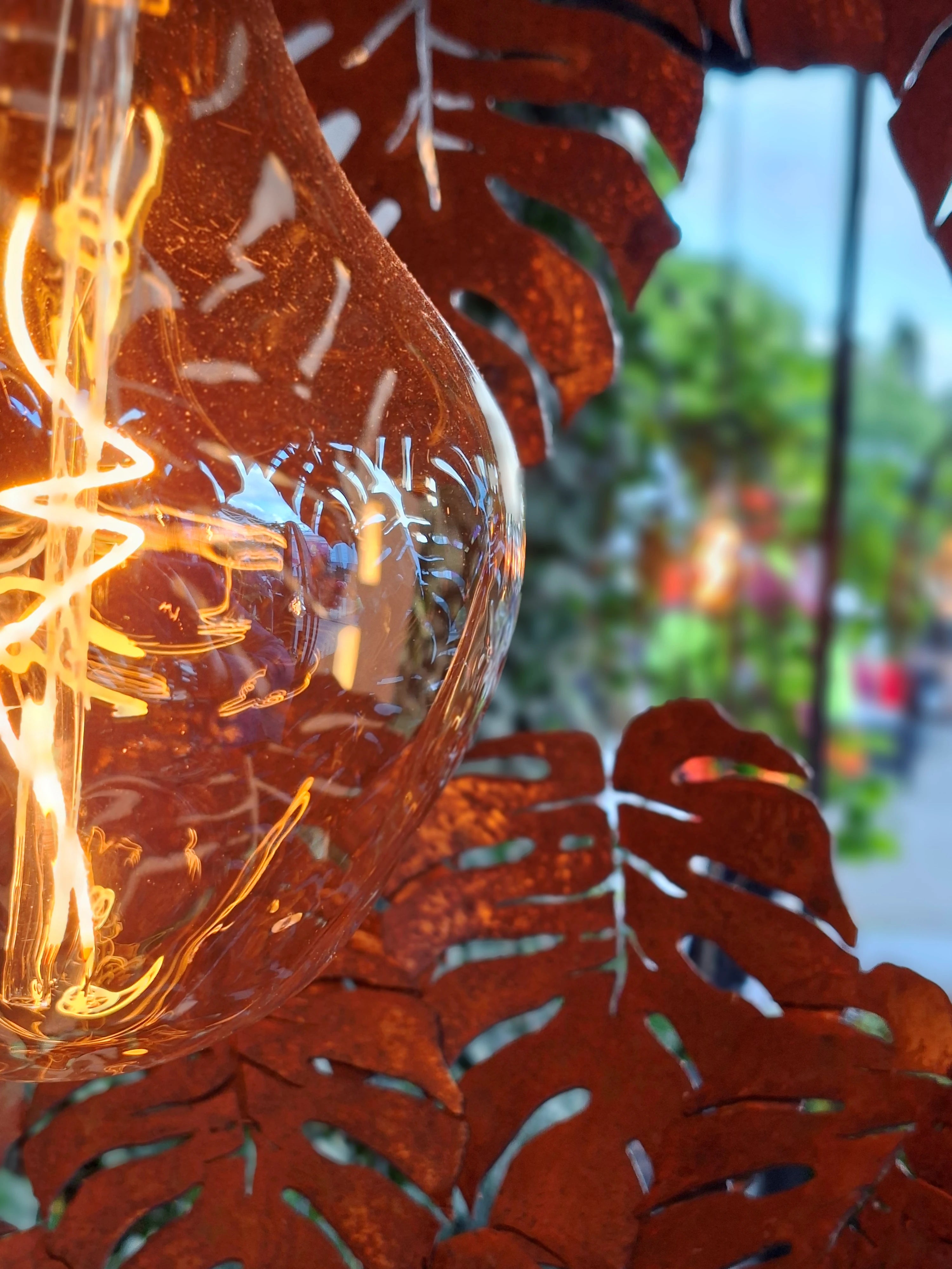 Decorative light bulb with red leaf-like casing in an outdoor setting