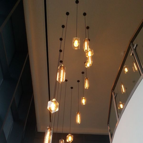 Modern chandelier with hanging light bulbs in a room with stairs.