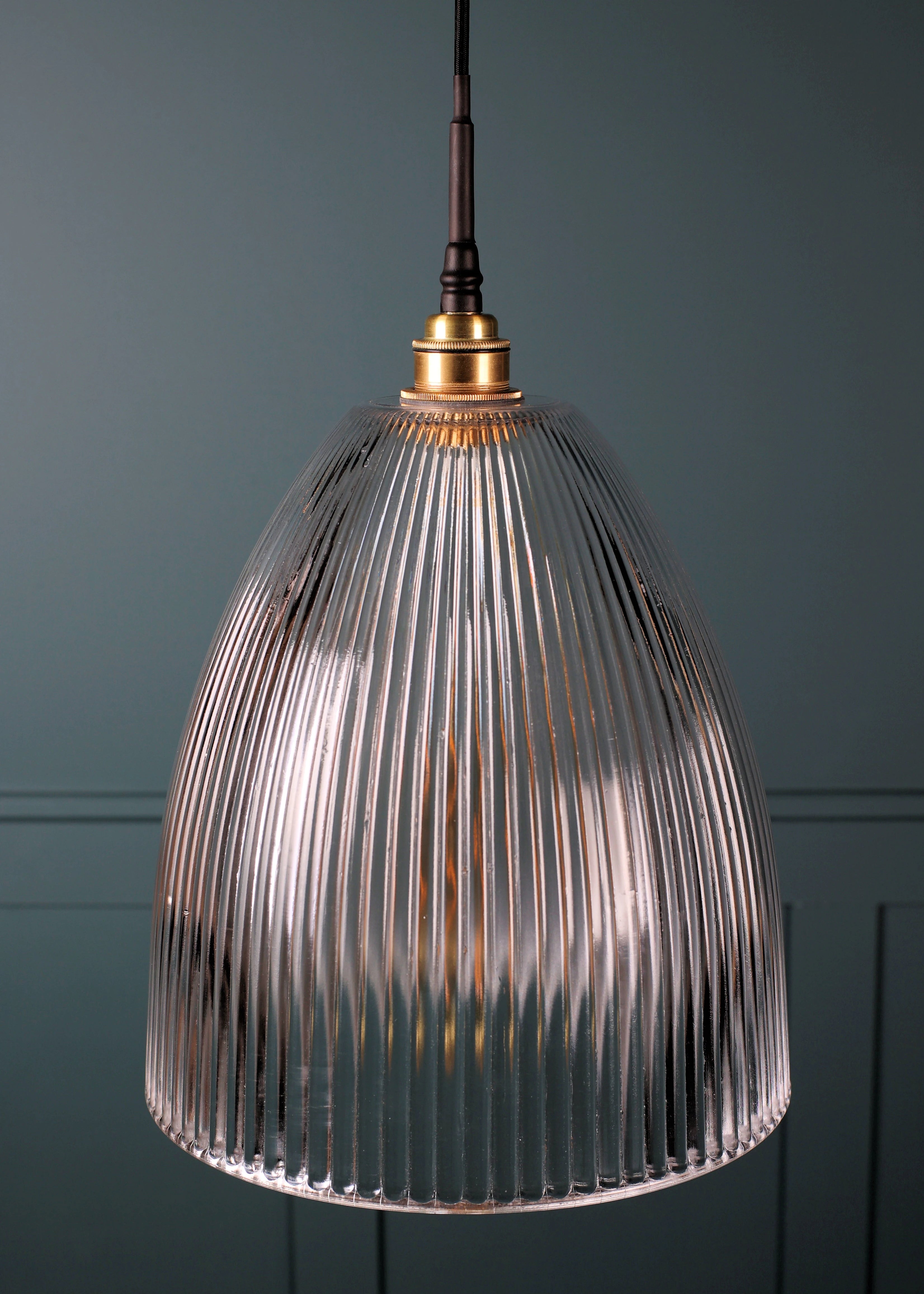 Large domed glass bathroom pendant light with brass lamp holder on teal coloured background