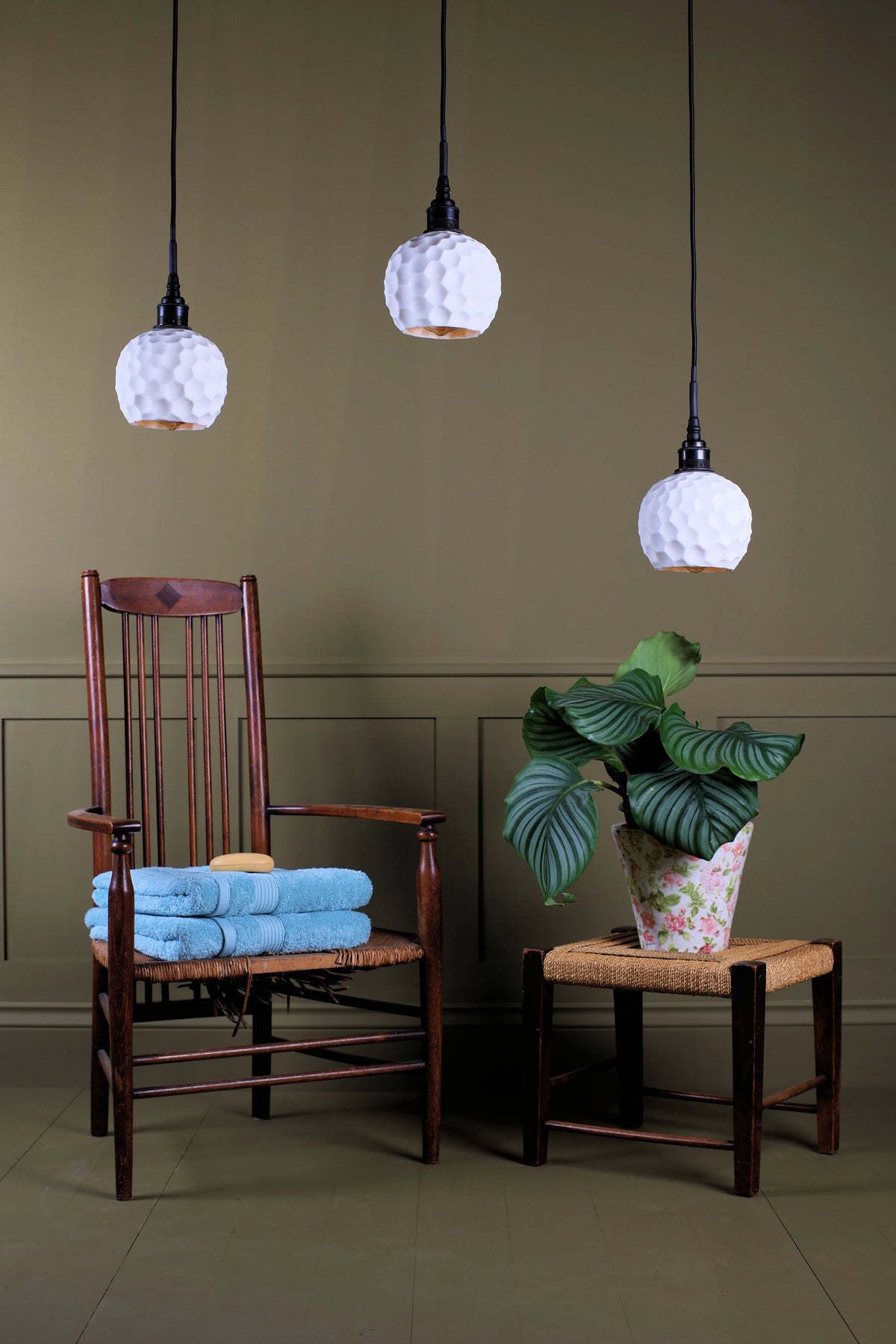 A cluster of ceramic beehive effect bathroom pendant lights hanging over wooden chair with pot plant and stool decoration