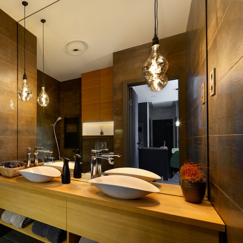 Decorative pendant lights hanging in modern bathroom with wooden countertop