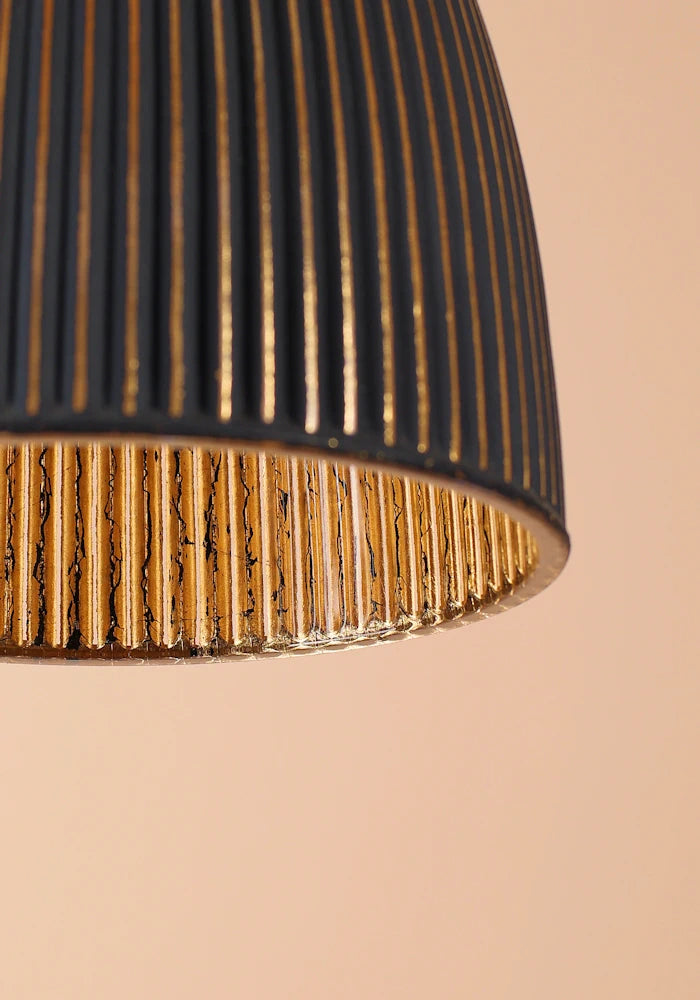 Close-up of a lampshade with black and gold ribbed design on a beige background