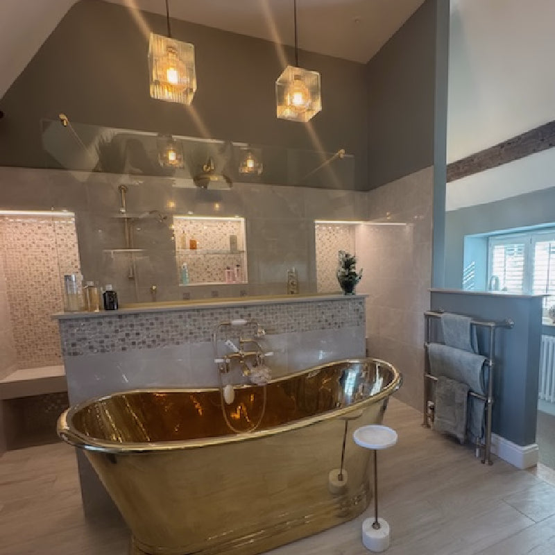 glass pendant lights hanging above gold bath in luxury bathroom