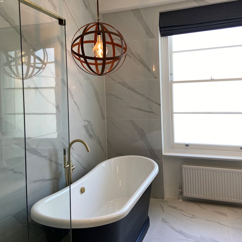 Modern bathroom with a freestanding bathtub, glass shower enclosure, and decorative IP44 Orbital light fixture.