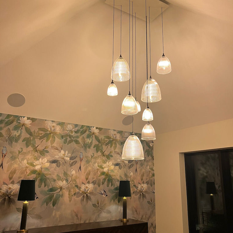 Modern glass pendant lights hanging in a room with floral wallpaper.