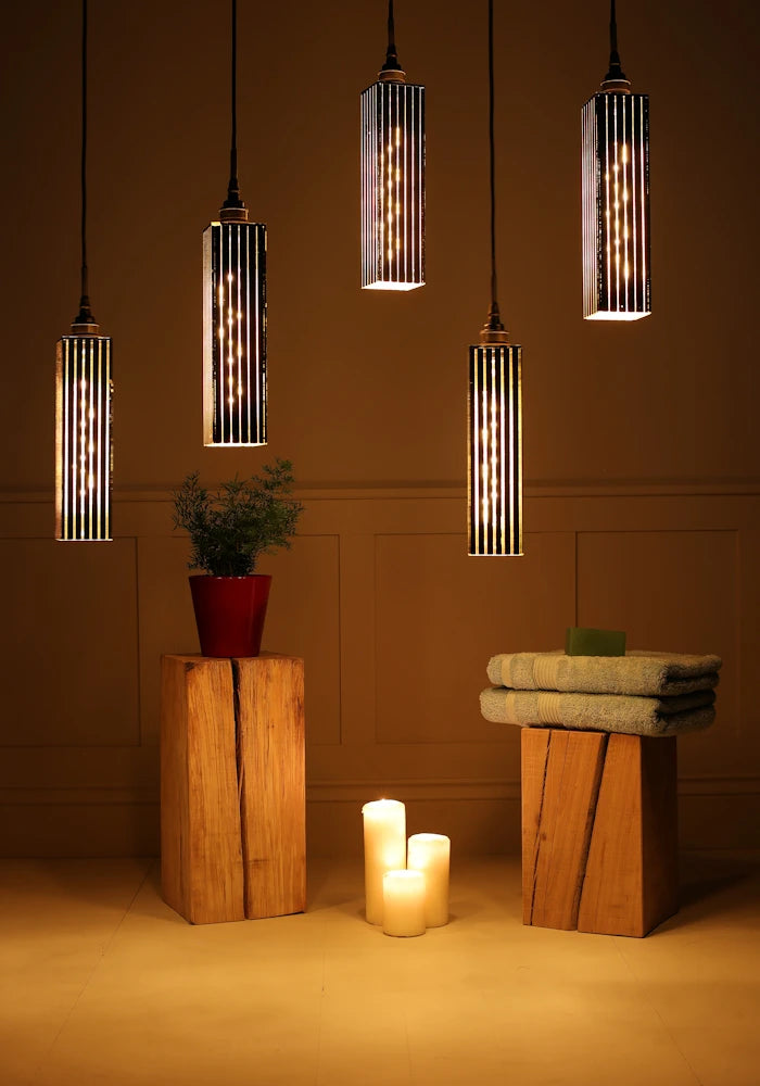 5 black and gold cluster bathroom pendant light with plant, candles and bath towels.