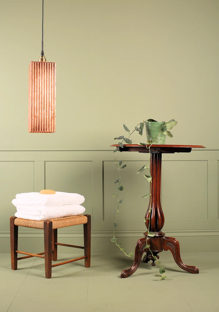 Large rectangular copper lead bathroom pendant light switched off, bath towels and ornate table.