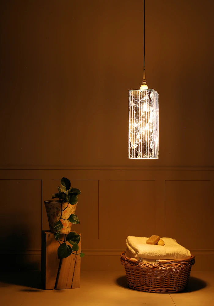 Large rectangular gold leaf bathroom pendant light with plant and bath towels in basket.