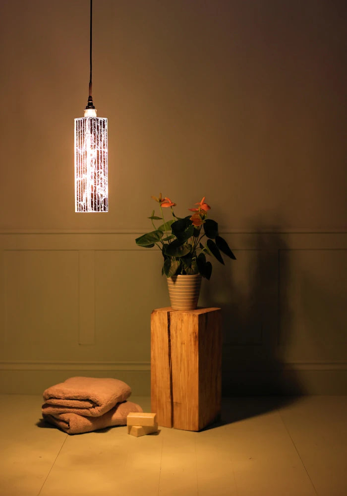 Long rectangular silver leaf bathroom pendant light casting shadows onto bath towels and pot plant.