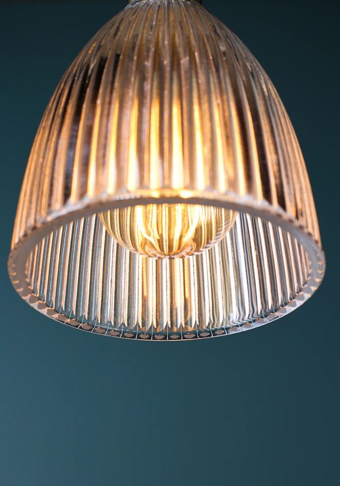 Close up image of light bulb in small ribbed glass bell shaped bathroom pendant light