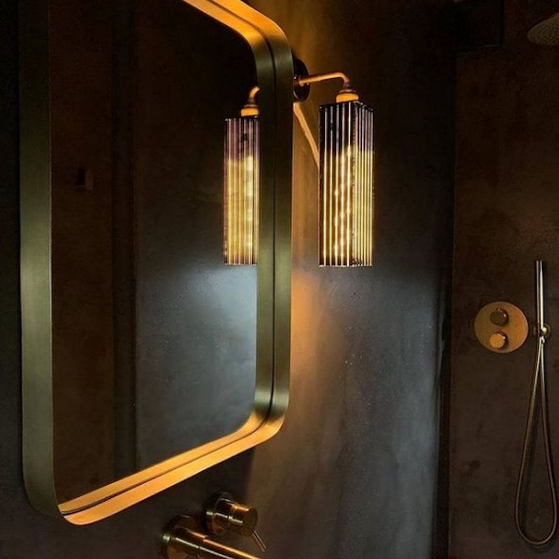 Decorative IP44 black and gold wall light fixture with a mirror on a dark wall.