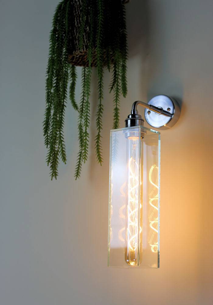 Elegant glass wall light with chrome fitting, green plant decor